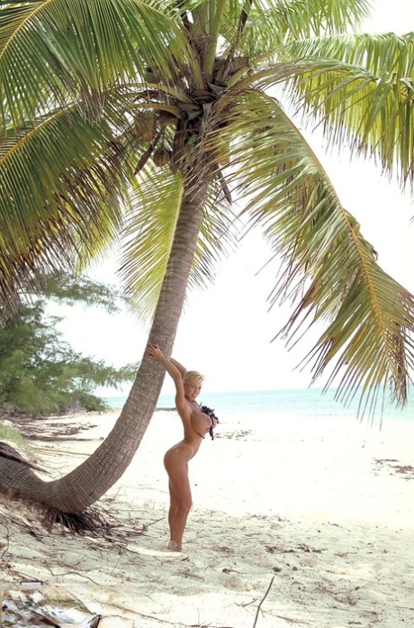 Blonde MILF Tiffany Towers on her knees in the sand with massive boobs hanging
