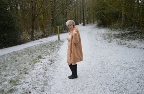 Older amateur Barby Slut exposes herself on snow-covered ground in a park