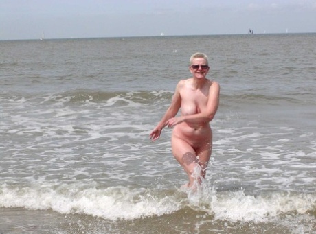 Mature lady Tiffany Pearl wears nothing but sunglasses while at the beach