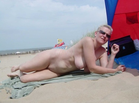 Mature lady Tiffany Pearl wears nothing but sunglasses while at the beach