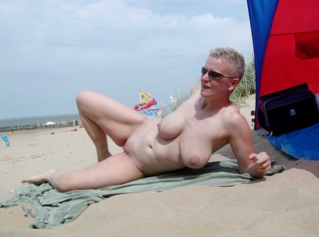 Mature lady Tiffany Pearl wears nothing but sunglasses while at the beach