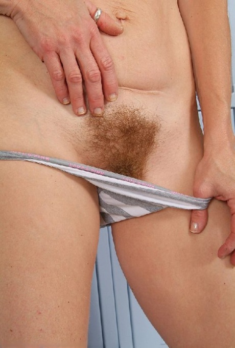Cute mom stripping in a locker room and reveals her hairy bush from panties