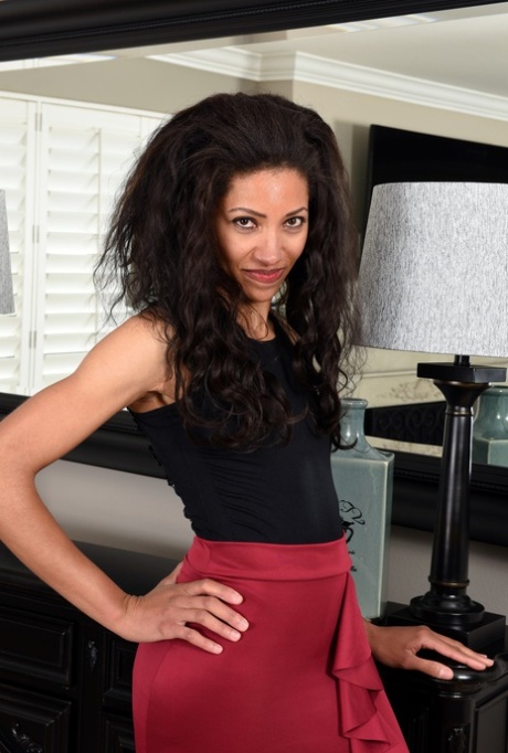 Mature ebony Cree Morena takes off her red dress and poses naked in her room