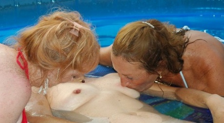 Playful mature sluts rubbing each other's love holes in the pool