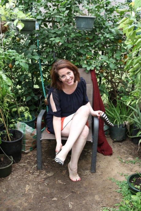 Busty mature lady Brie playing with her bald pussy in the garden